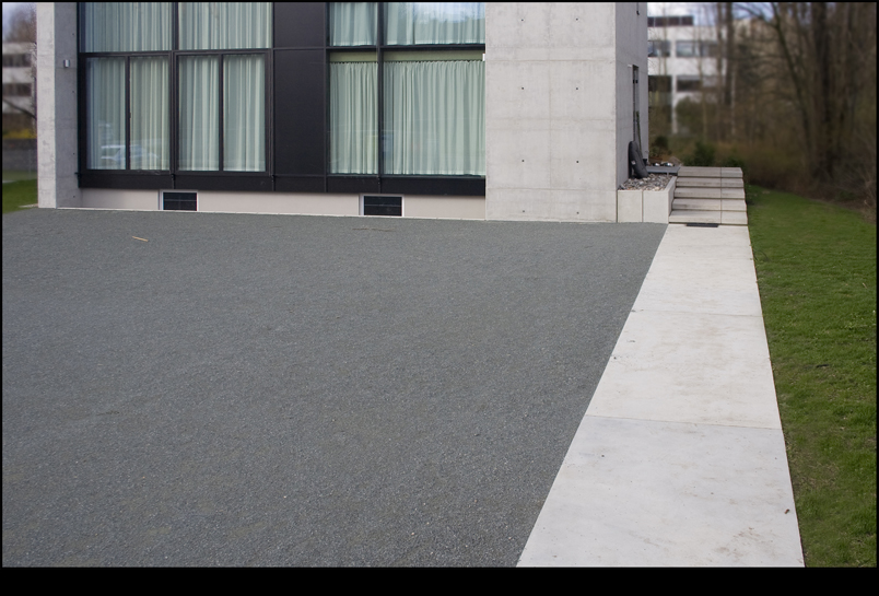 Grundstücksvorfahrt mit Ortbetonweg und einem großflächigen Vorplatz aus wassergebundener Wegedecke